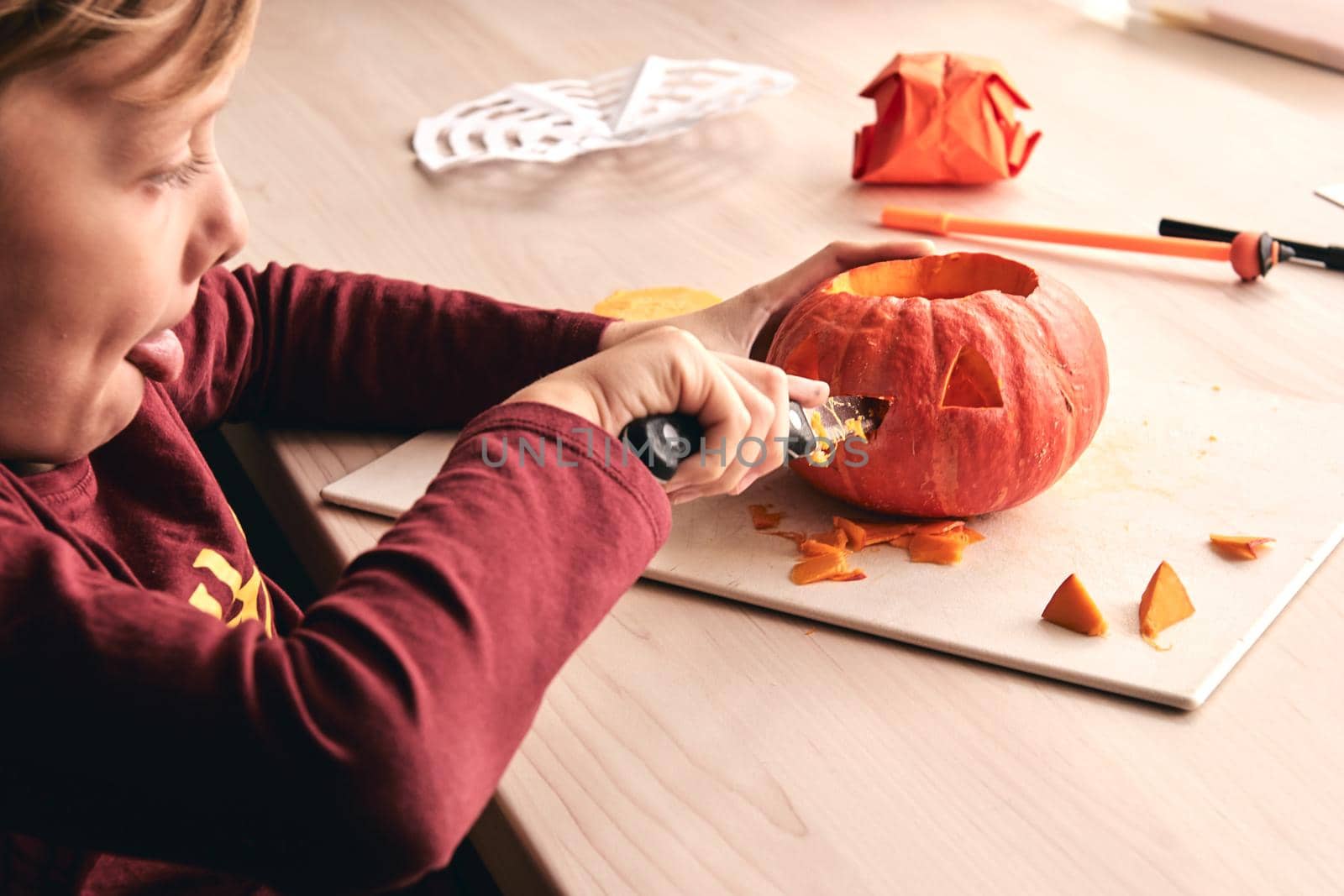 Halloween, decoration and holidays ideas- close up of kid with knife carving pumpkin or jack-o-lantern. 6 years boy has homefamily fun activity. Mom spending time with son together.