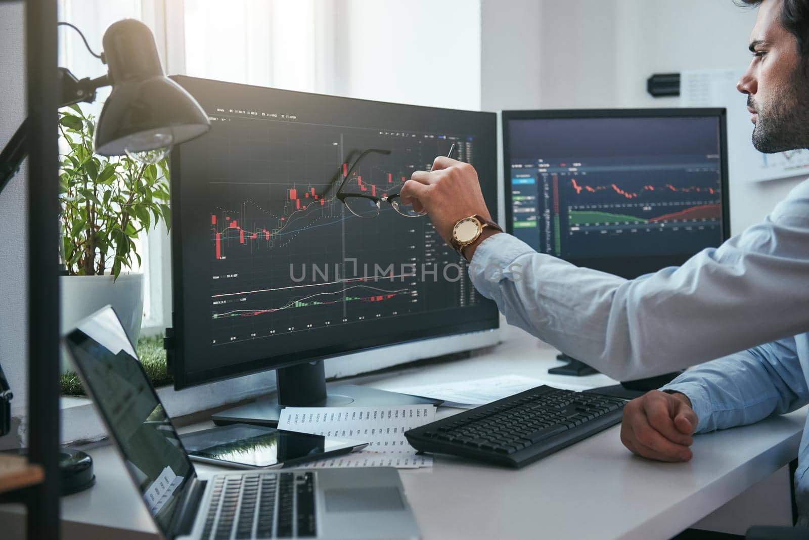 Forex market. Young trader is pointing at graphs on computer screen and analyzing data while working in his modern office. Stock exchange. Trade concept. Investment concept