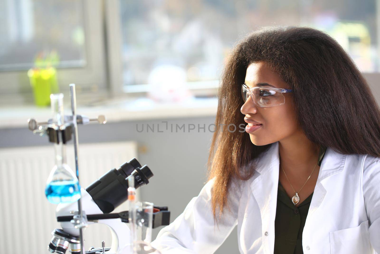 Black female chemist student conducting research using a microscope for bacterial contamination of water searching for a vaccine to treat diseases in medicine doctor concept