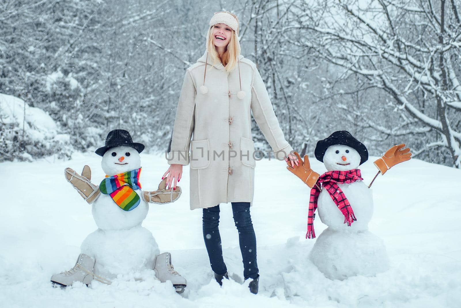 Winter woman. Funny Girl Love winter. Winter portrait of young woman in the winter snowy scenery. Cute girl making snowman on snowy field outdoor