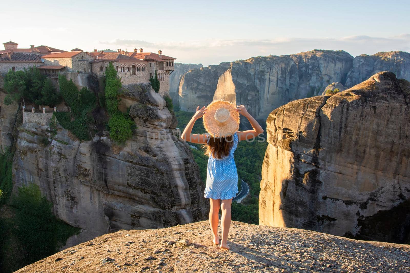 Young woman in blue dress enjoying nature on the mountains near Meteora monasteries in Greece.
