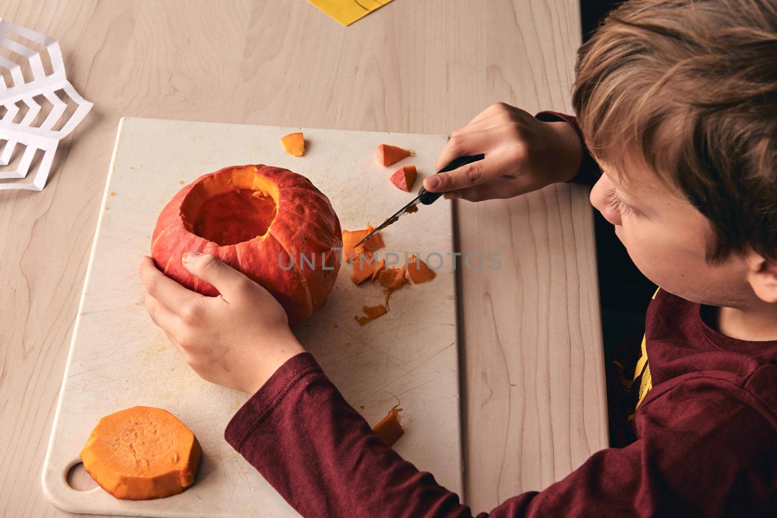 Halloween, decoration and holidays ideas- close up of kid with knife carving pumpkin or jack-o-lantern. 6 years boy has homefamily fun activity. Mom spending time with son together.