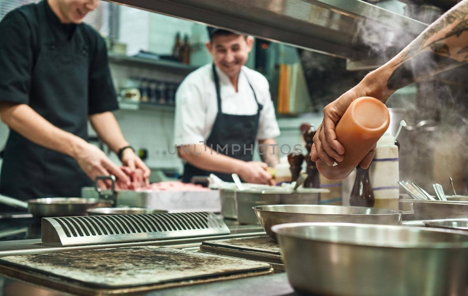 Professional team. Cheerful young cooks preparing food together in a restaurant kitchen. Cooking concept