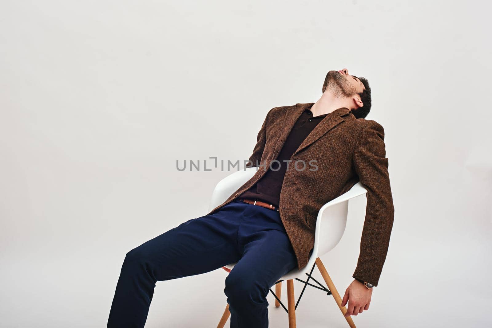 Sick and tired. Stylish dark-haired businessman sitting on a chair, leaning back and looking at the ceiling isolated over white background by friendsstock