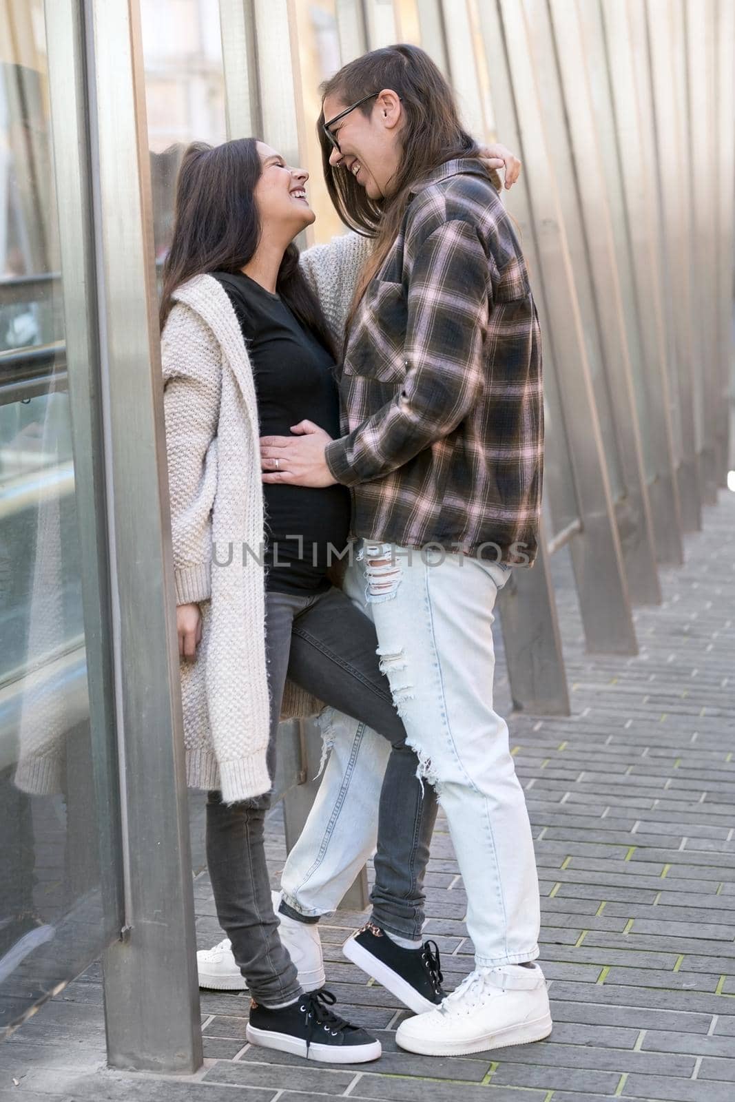 Young affectionate pregnant lesbian couple standing outdoors in city. High quality photo.