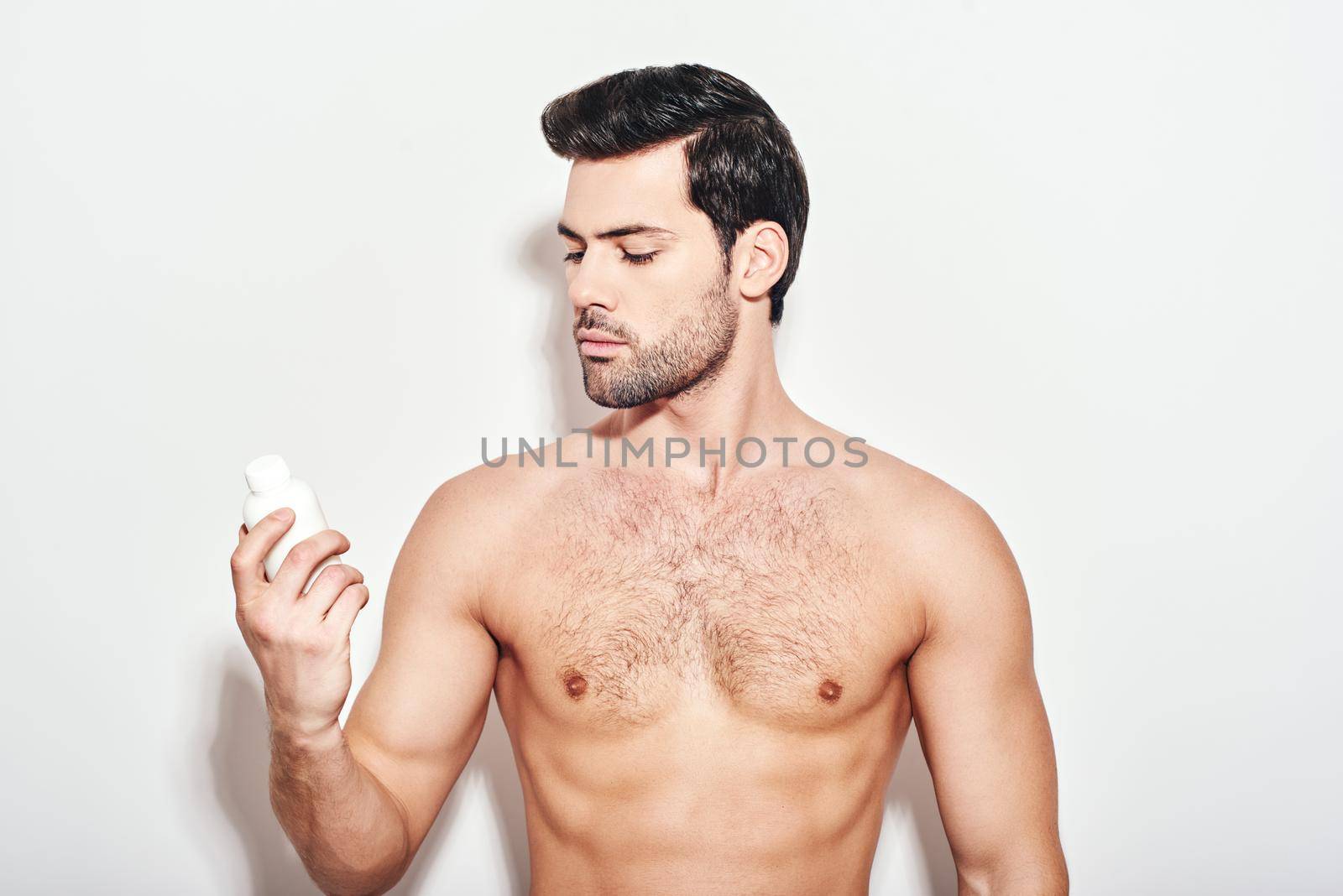 Handsome man holds the moisturizer that he uses to make his skin smooth and clean from impurities. Concept of beauty and facial cleansing, moisturizing and relaxation creams