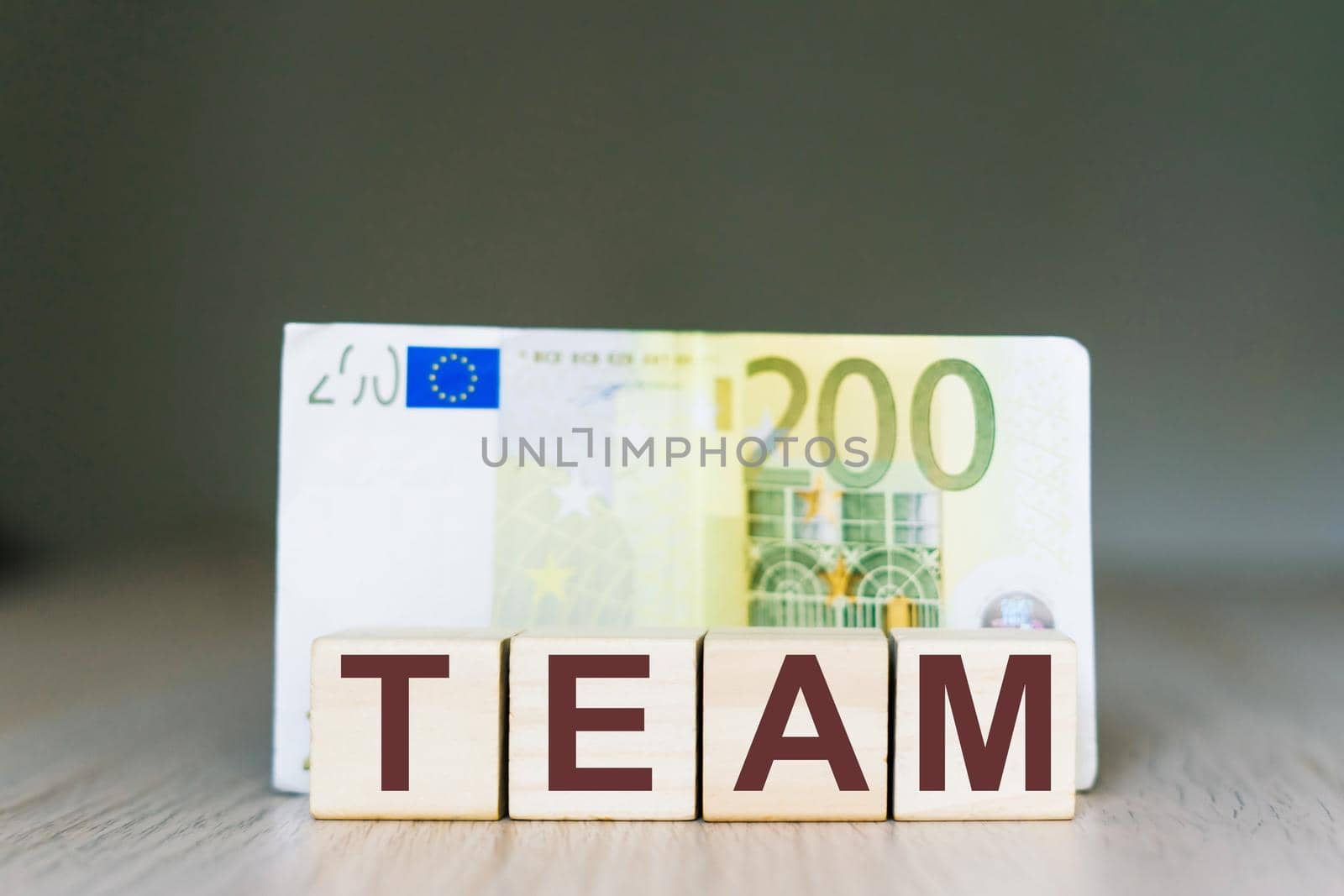 Team word on wooden cubes blocks, money 200 Euro banknotes. Management big salary career concept. by Zelenin