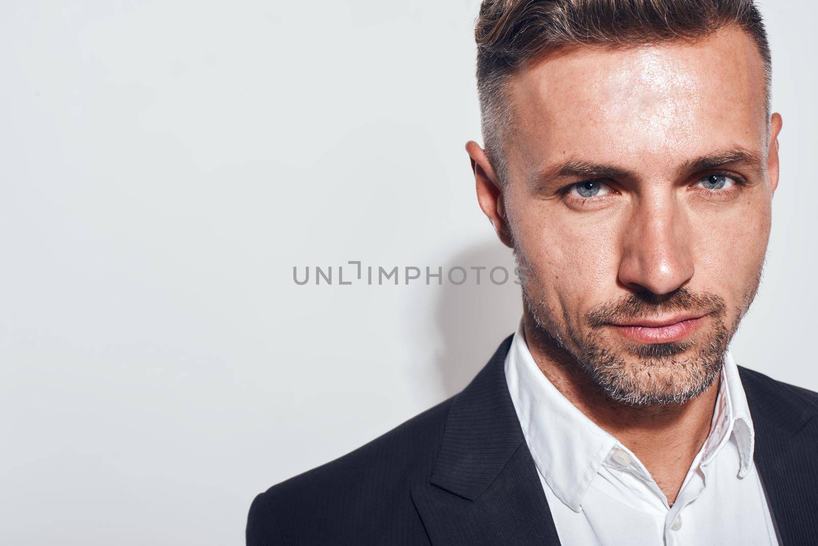 Confidence. Cropped photo of bearded charming businessman in classic suit looking at camera while standing against grey background by friendsstock