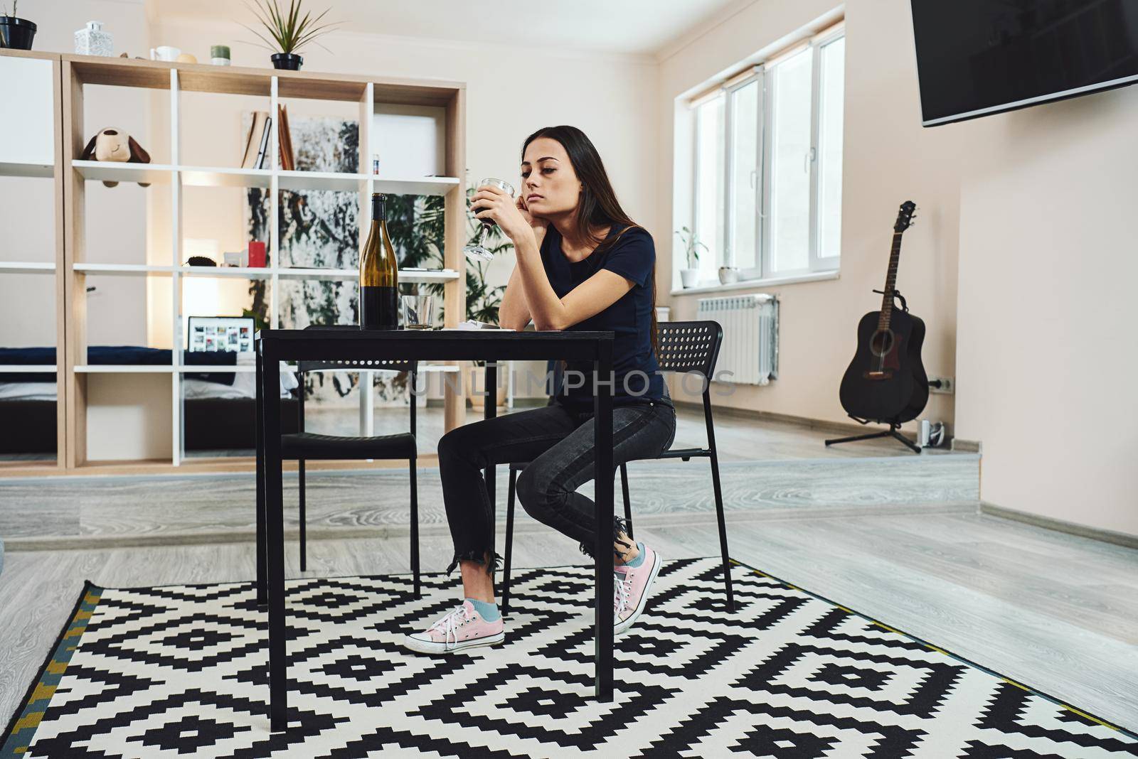 It always seems impossible until it s done. Young woman drinking red wine alone in kitchen at home. Female alcoholism concept. Protest in the treatment of alcohol addiction. by friendsstock