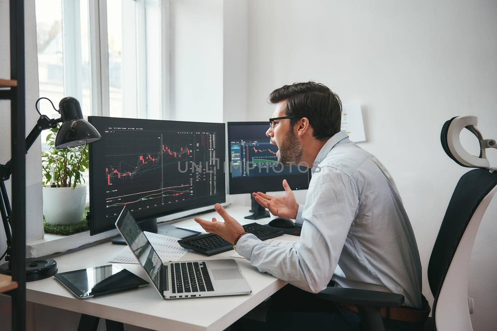 No way Shocked young businessman or trader in formalwear is shouting and gesturing while looking at trading charts and financial data in the office. by friendsstock