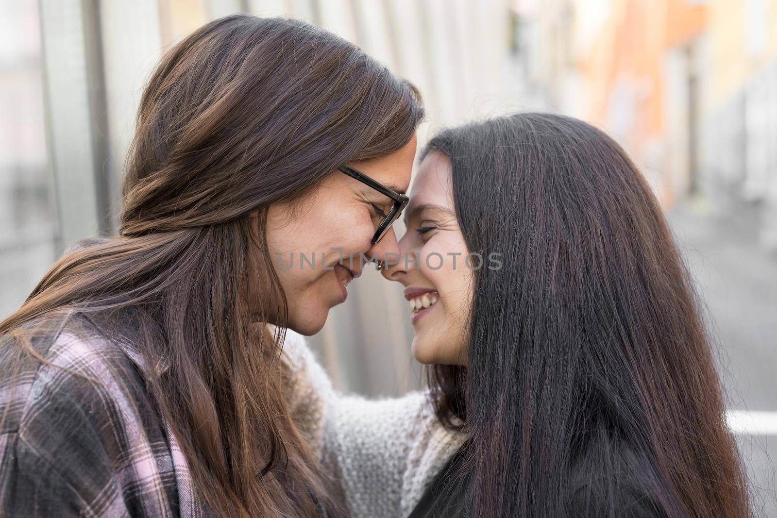 Young affectionate lesbian couple standing outdoors in city by HERRAEZ