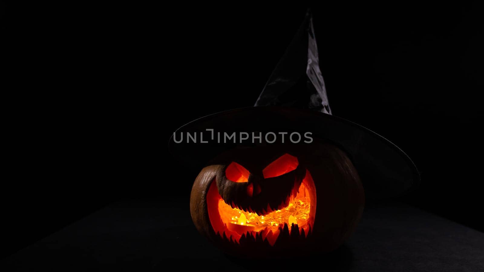 Glowing pumpkin in a witch hat in the dark. Jack o lantern. by mrwed54