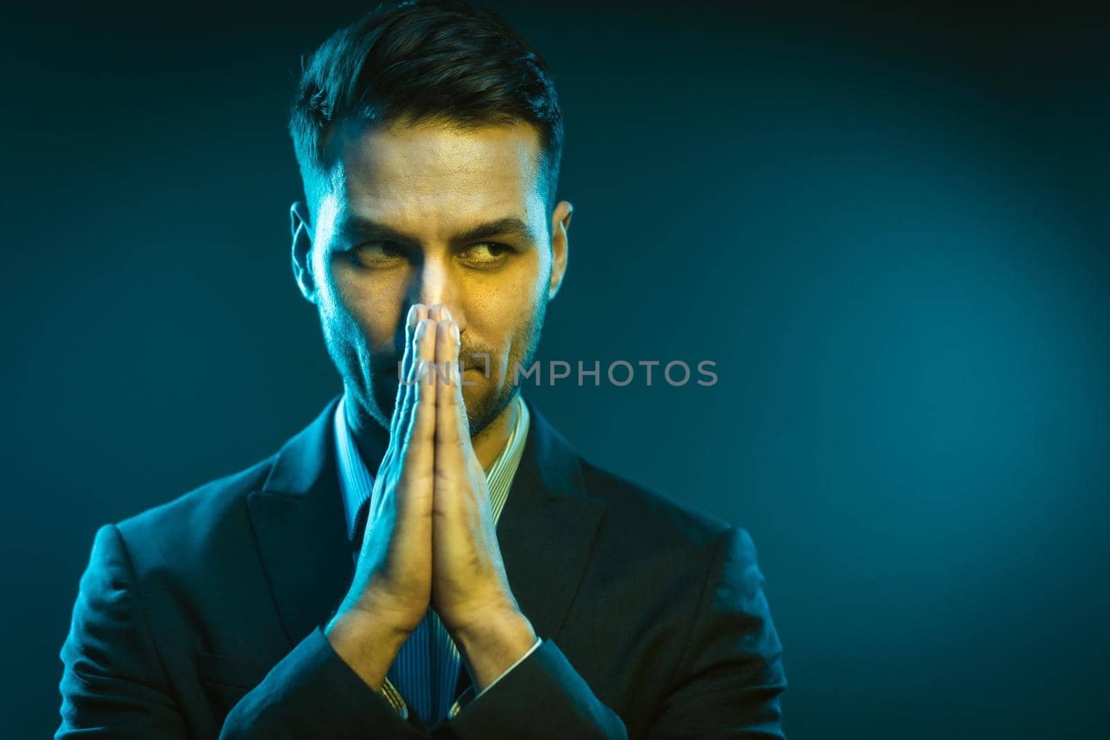 Serious Business Man Has an Idea How to Improve His Business. Strong White Man With Folded Hands in Creative Neon Light. Close-Up Portrait on Blue Background. High quality photo