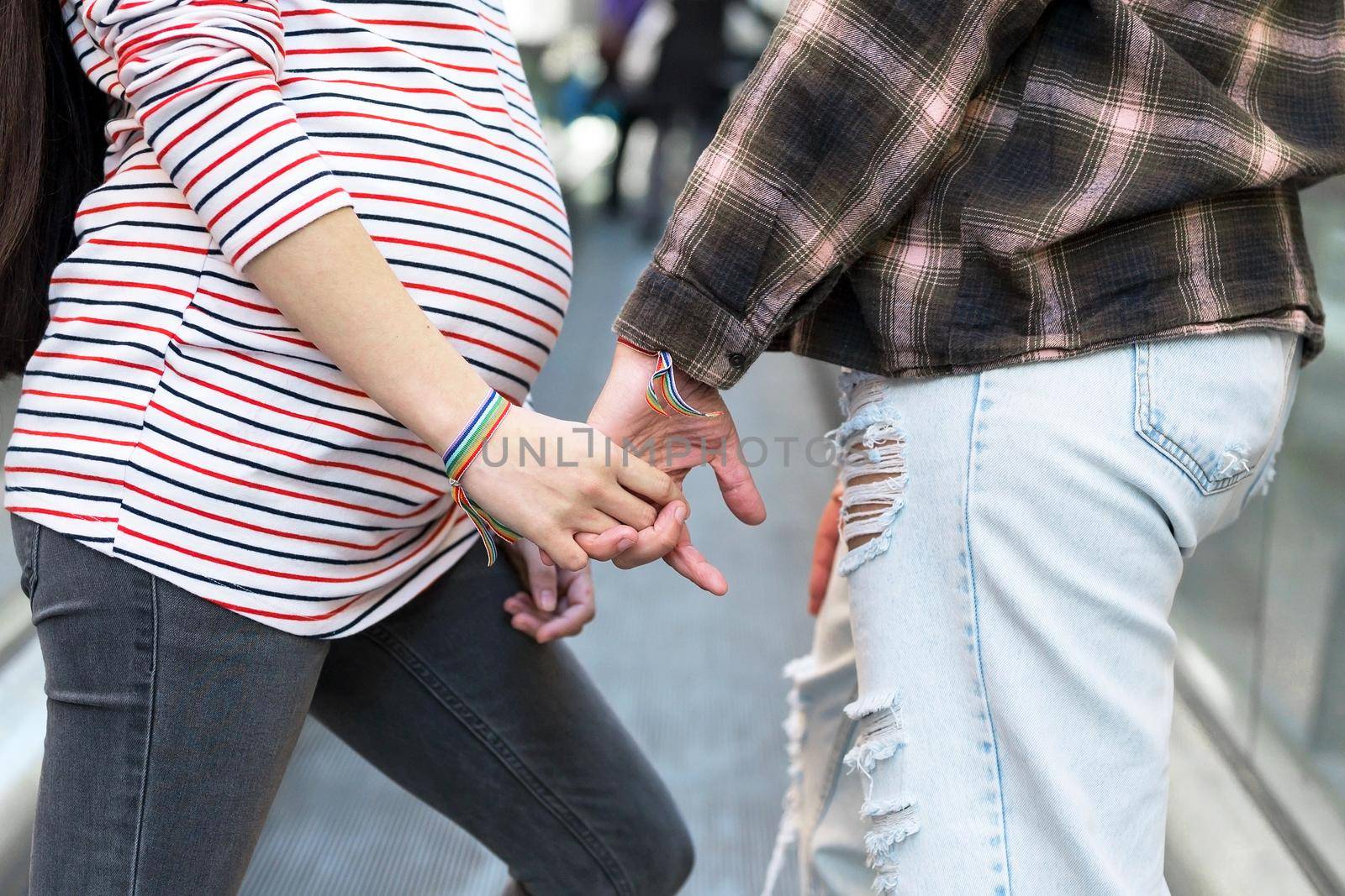Close up of Unrecognizable Lesbian Pregnant Couple holding hands outdoors. by HERRAEZ