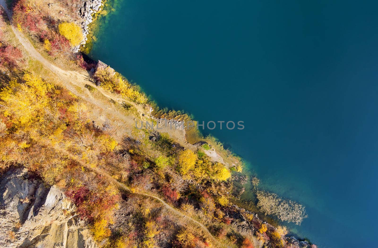Panoramic top view quarry artificial lake formed during mining stone in autumn season