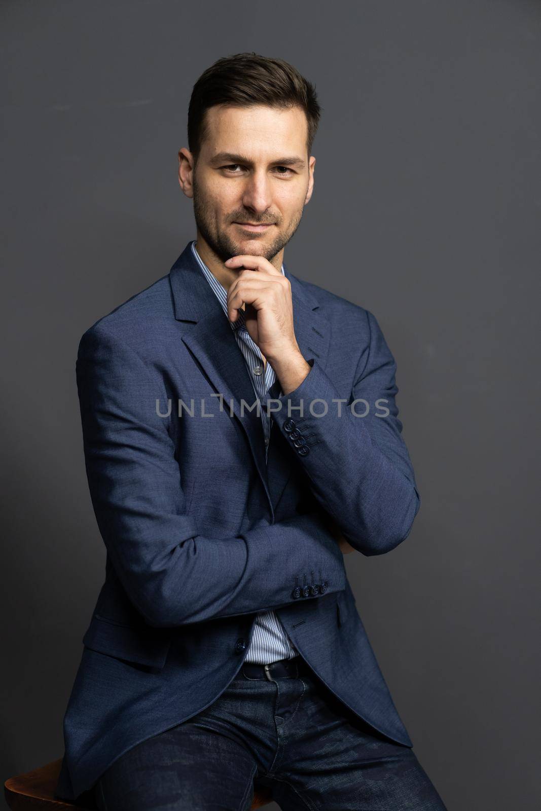 Elegance Businessman in a Blue Formal Slim Fit Blaser Gazes Straight to the Camera, Elegant Brown Haired Man Posing in Studio on a Gray Background, . High quality photo