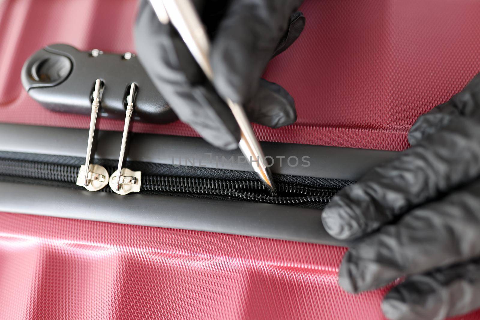 Gloved hands mending a snake on a suitcase, close-up. Shoemaker tailor tool for repairing snake on bags and clothes, tailor shop