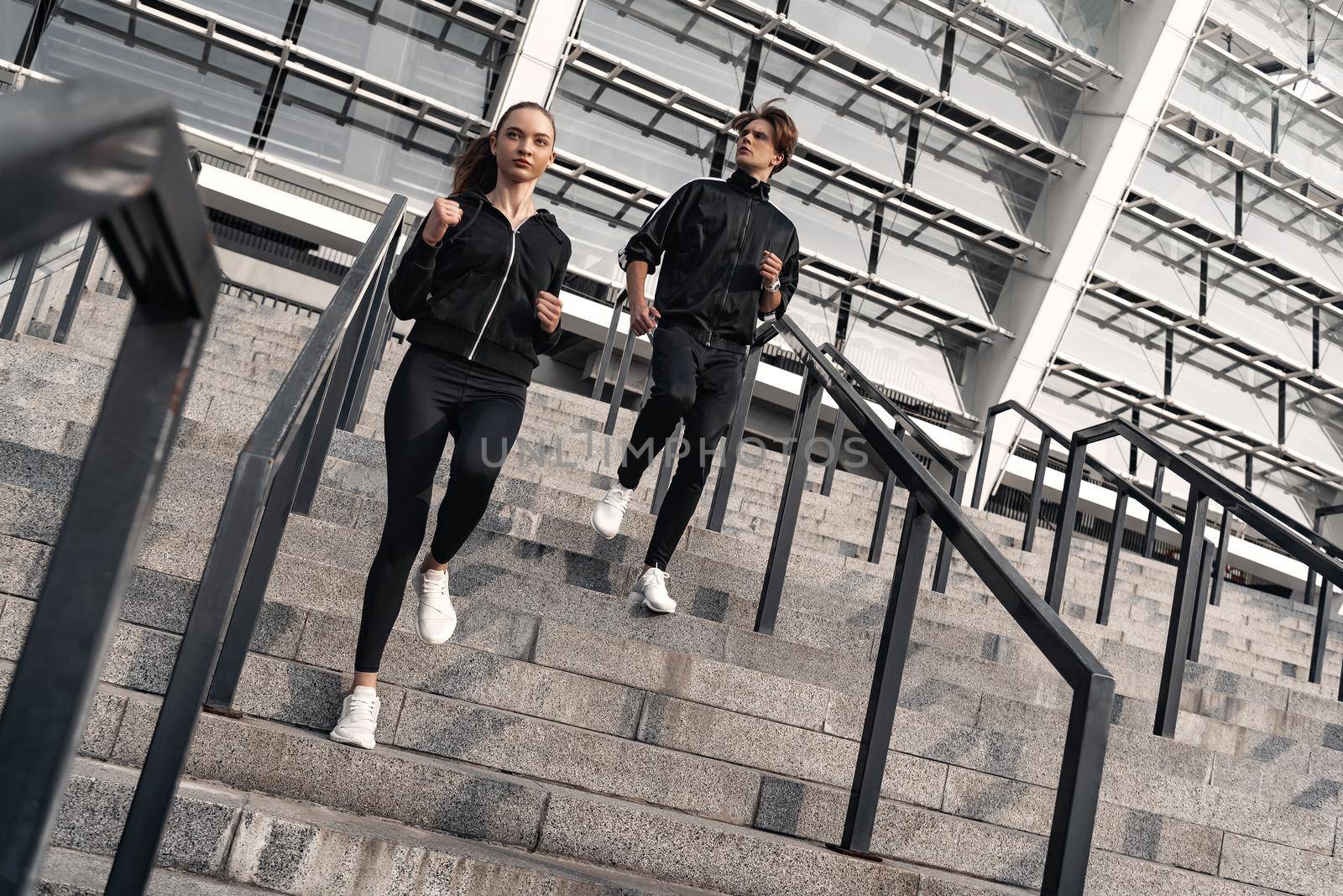 Early morning workout. Young couple running downstairs by friendsstock