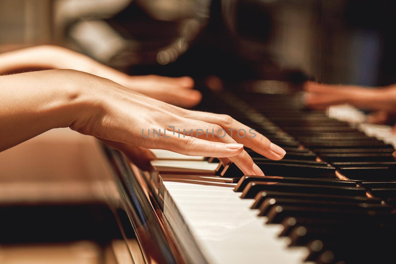 Favorite classical music...Close up view of gentle female hands playing a melody on piano while taking piano lessons. Musical instrument. Music education. Piano keyboard