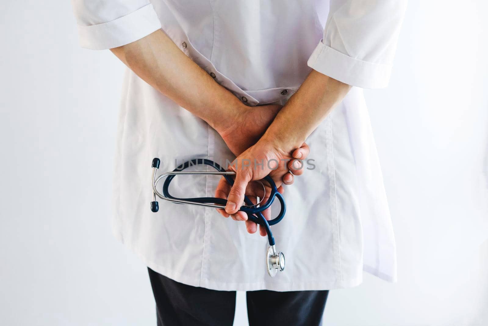 The doctor stands with his back and holds a stethoscope in his hands. International doctor's day. Doctor on the front line.