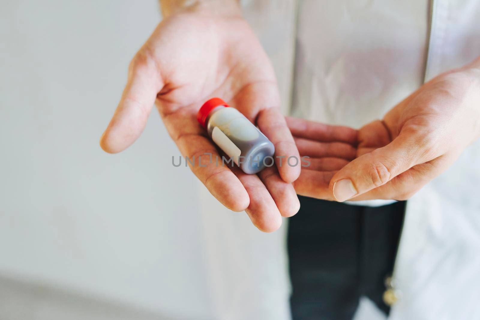 The doctor is holding a tube of medicine in his hand. Vaccine against the virus. Vaccine Covid-19. In the hands of a medical officer, the vaccine against the virus. The doctor is on the front line.