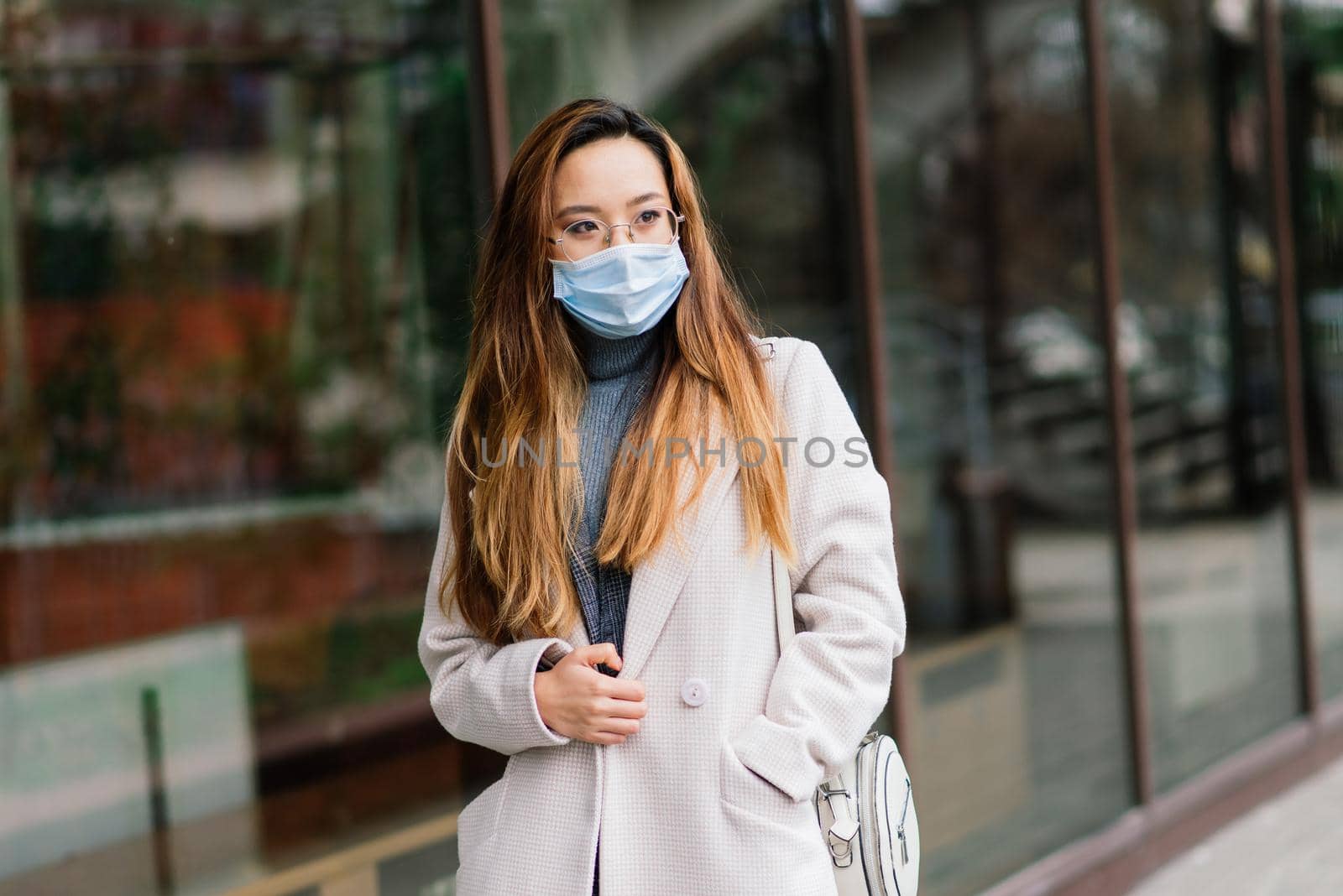 Young asian woman wearing face mask is standing at a domestic street.