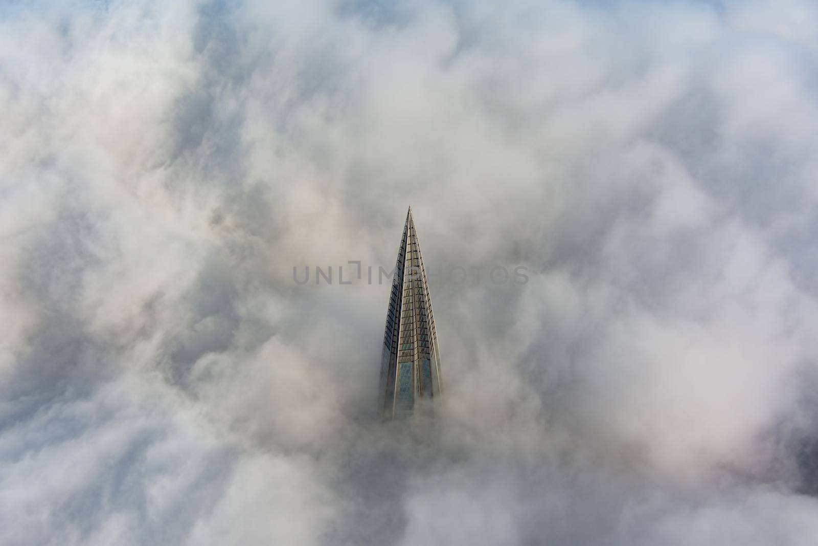 Russia, St. Petersburg, 14 October 2021: The top of the tallest skyscraper in Europe above the clouds, the building of the Gazprom oil company, the spire of a metal and glass structure. High quality photo