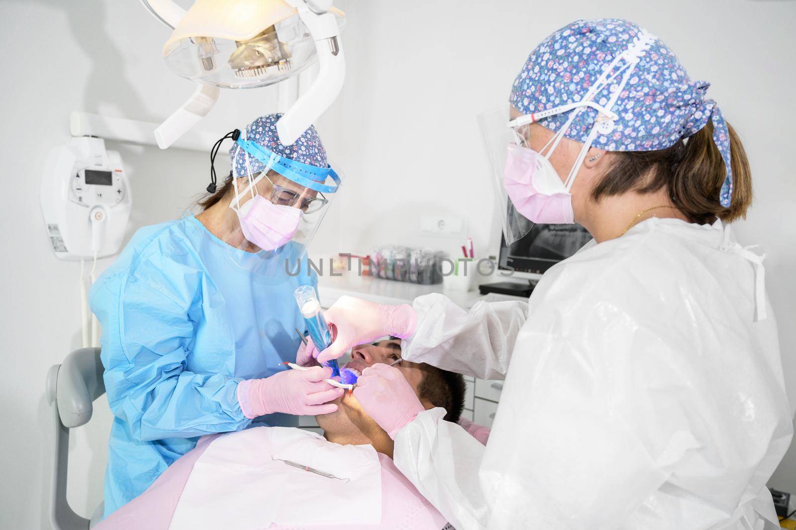 Medical dentist team in dental office treating male patient . High quality photo