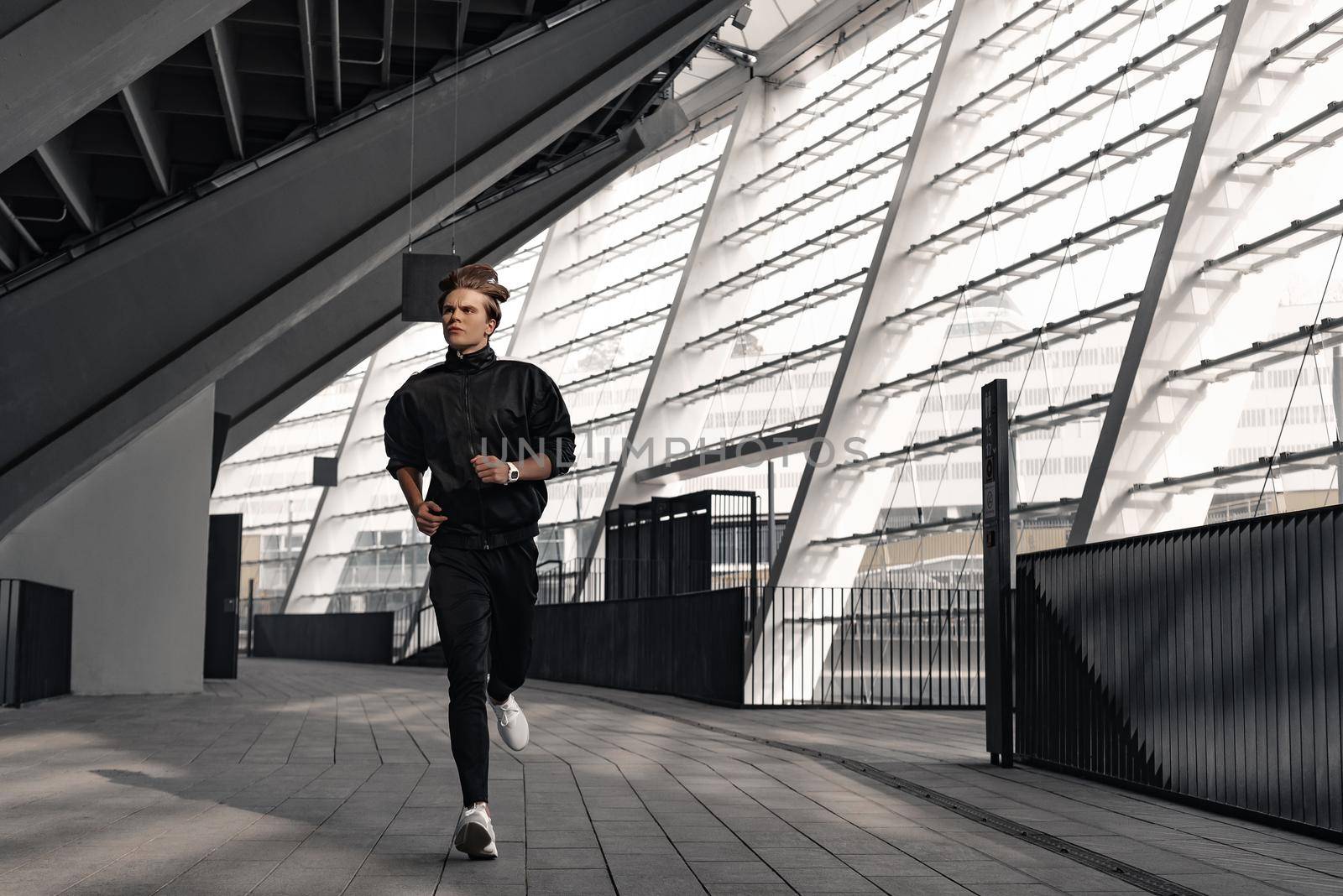 Young athlete is running near the stadium. by friendsstock