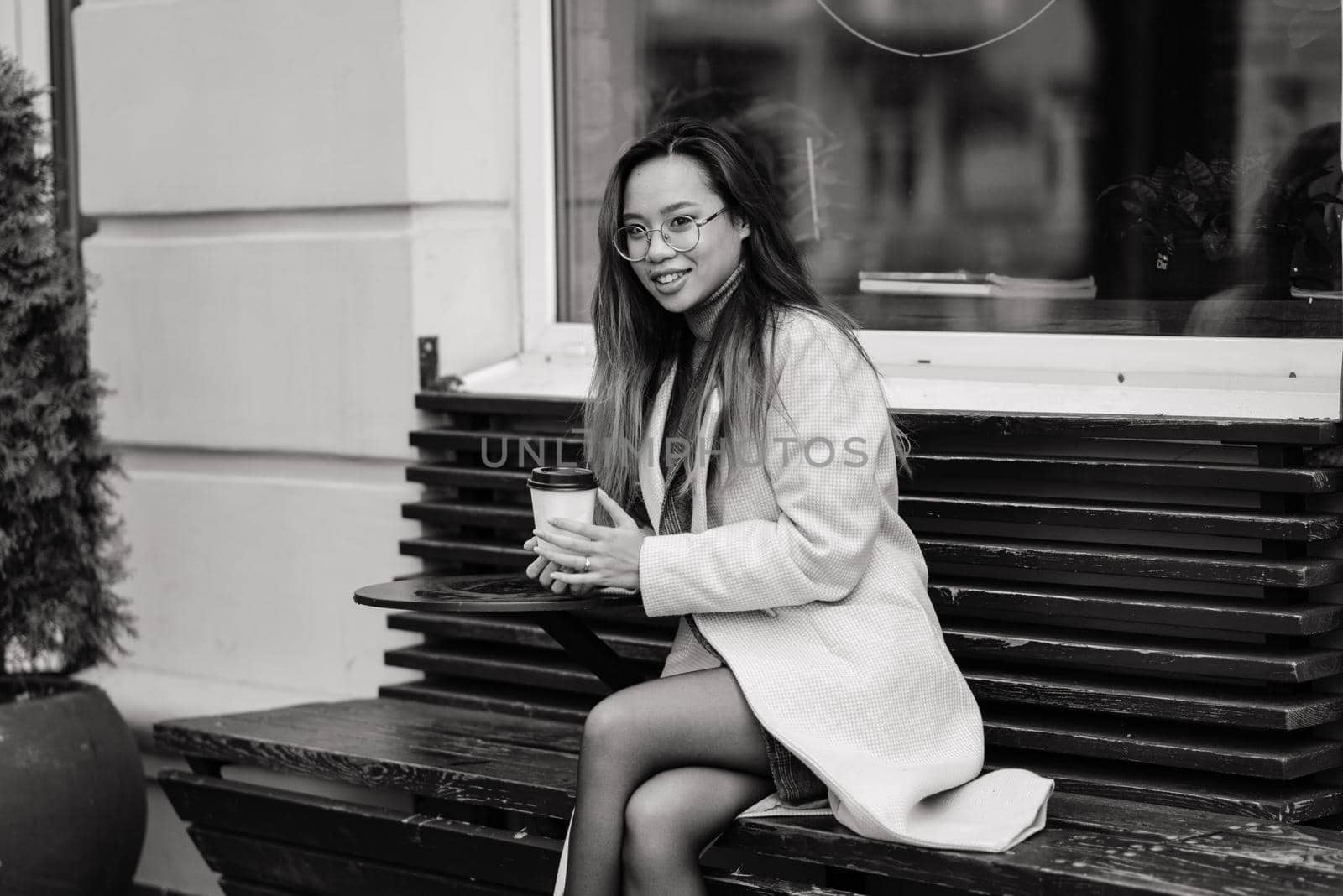 Charming asian woman with beautiful smile reading good news on mobile phone during rest in coffee shop, Happy female watching her photos on cell telephone while relaxing in cafe during free time.
