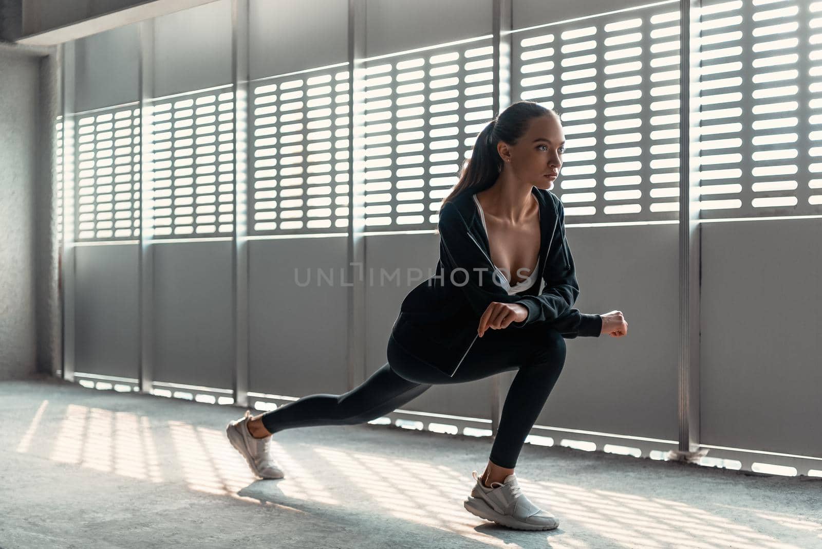 Young woman is doing warming up exercises near the stadium by friendsstock