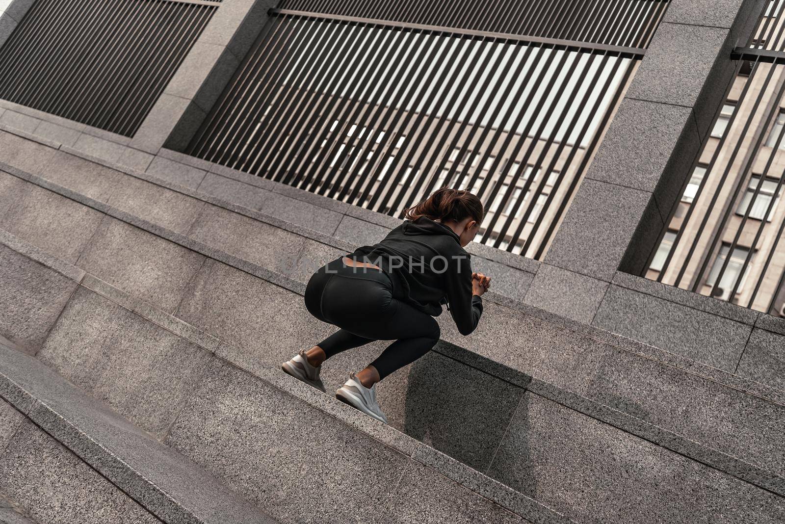 Young woman doing leg exercises with stone stairs by friendsstock