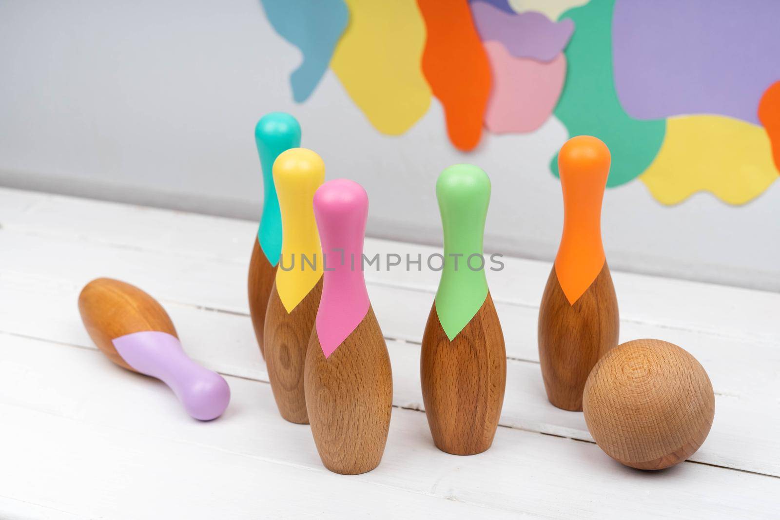 Skittles and a ball made of natural material. Bowling for children made of wood. Set for bowling. Children's wooden toys. Bright background.