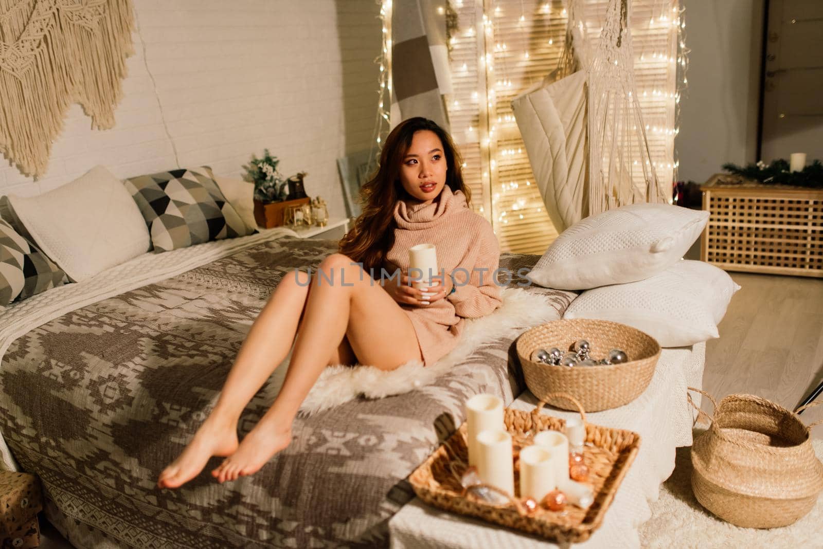 Pensive young pretty asian woman with burning candles on Christmas eve making wish by Zelenin