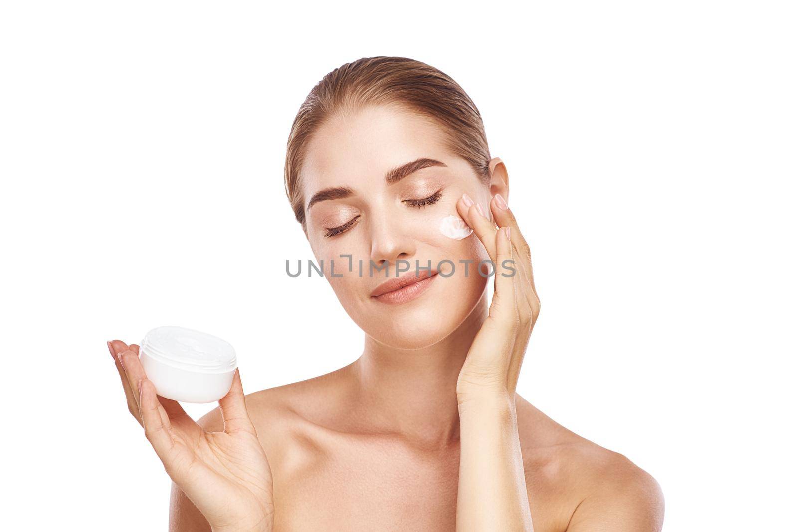 Beautiful womans face with facecream close up studio photo on white background. Light hair, grey eyes, closed eyes