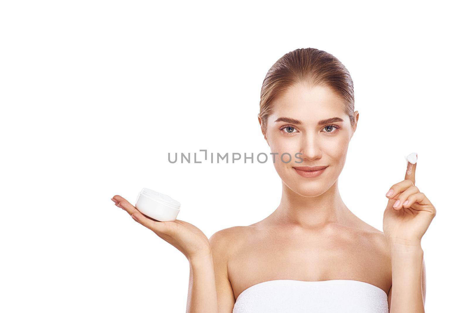 Beautiful womans face with facecream wearing white towel close up studio photo on white background. Light hair, grey eyes