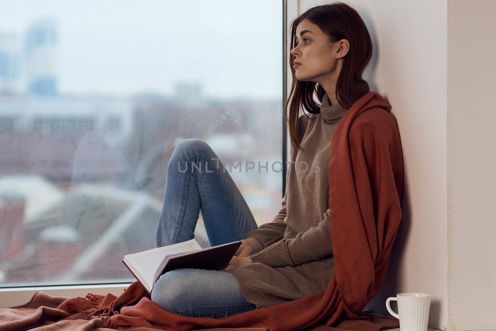 woman with a book near the window with a cup of coffee. High quality photo