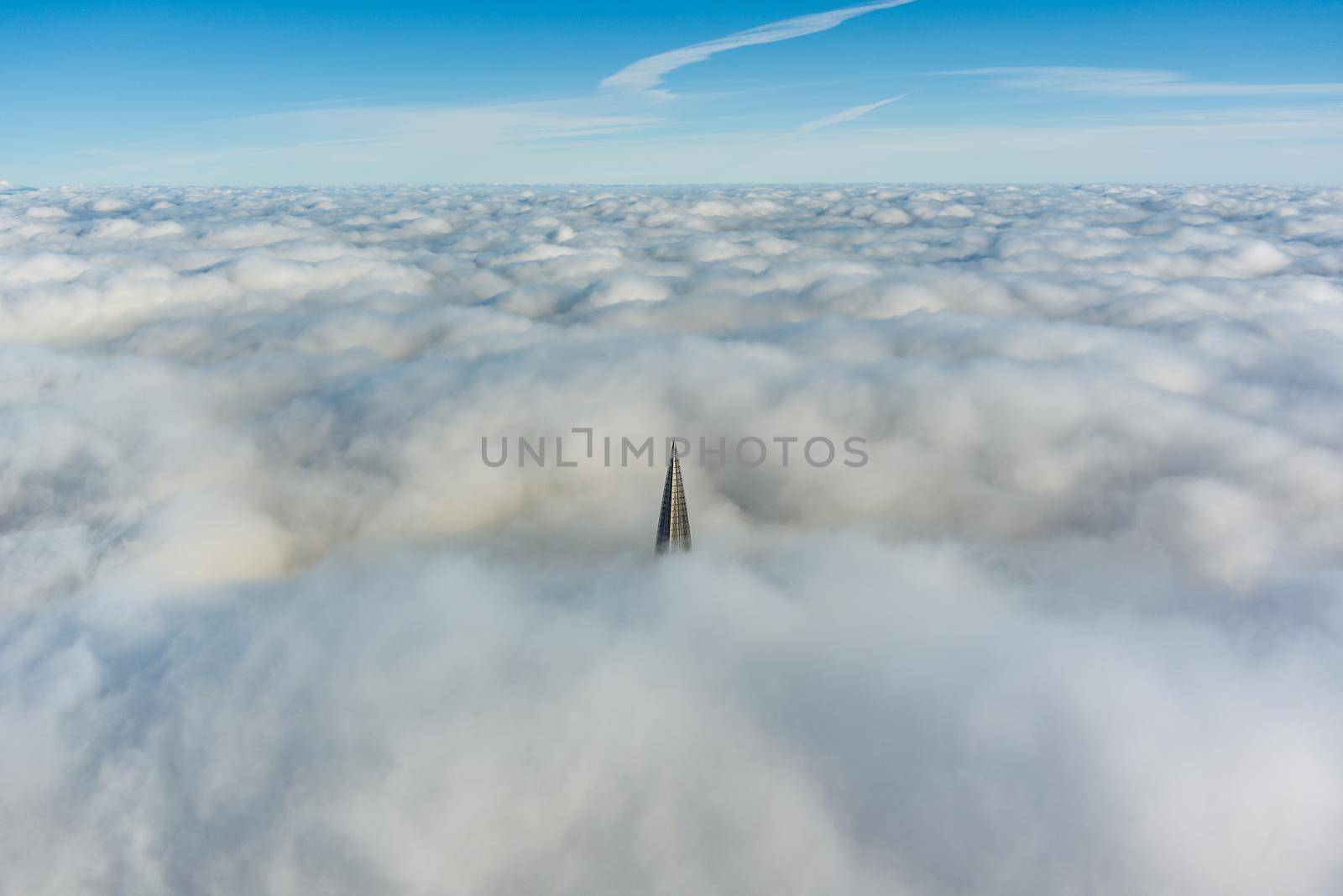 Russia, St. Petersburg, 14 October 2021: The top of the tallest skyscraper in Europe above the clouds, the building of the Gazprom oil company, the spire of a metal and glass structure. High quality photo