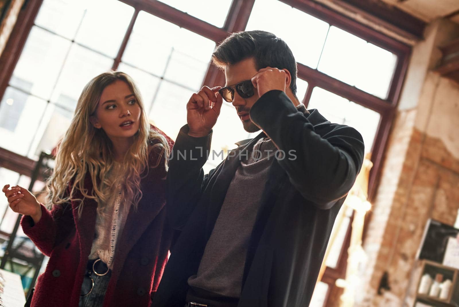 Happy young couple are buying sunglasses at small street market by friendsstock