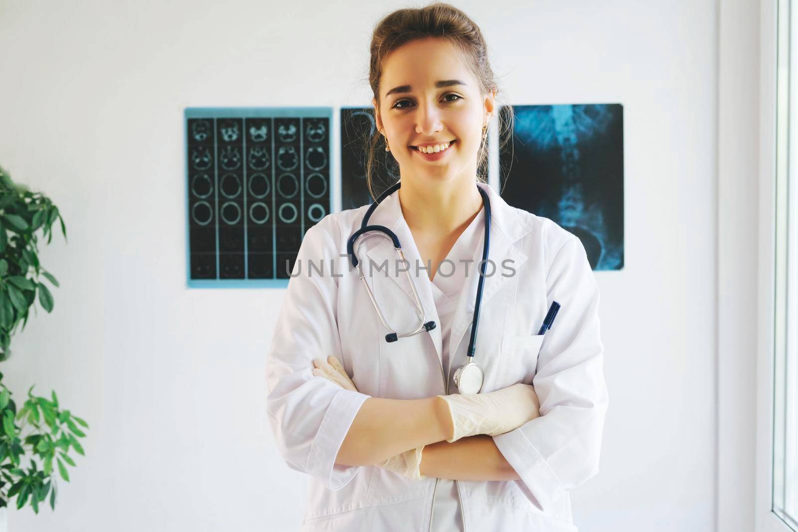 Female doctor at work in public medical clinic and examining x-ray plates of lungs. The girl doctor works on the front line. Medical and radiology concept. International Doctor's Day.