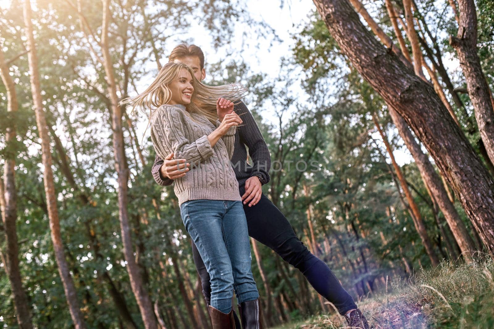 Outdoor happy couple in love posing in autumn forest. Young woman and man are dancing outdoor