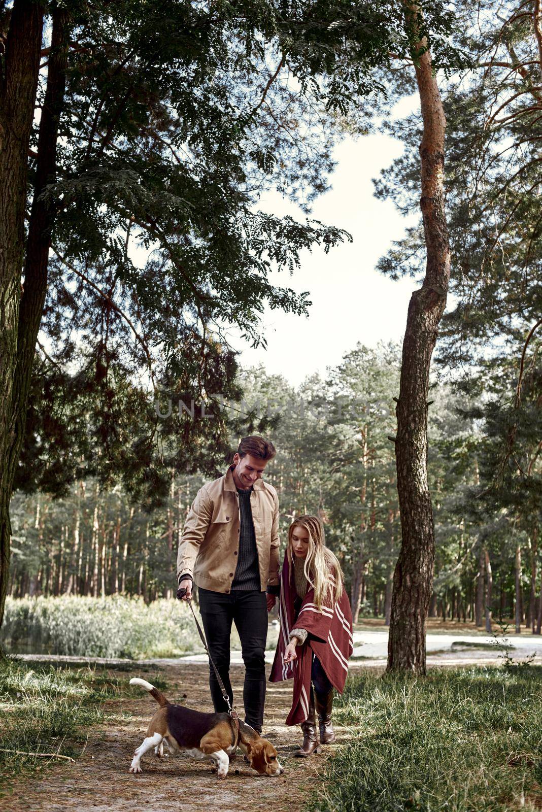 Young couple are walking with dog in forest by friendsstock