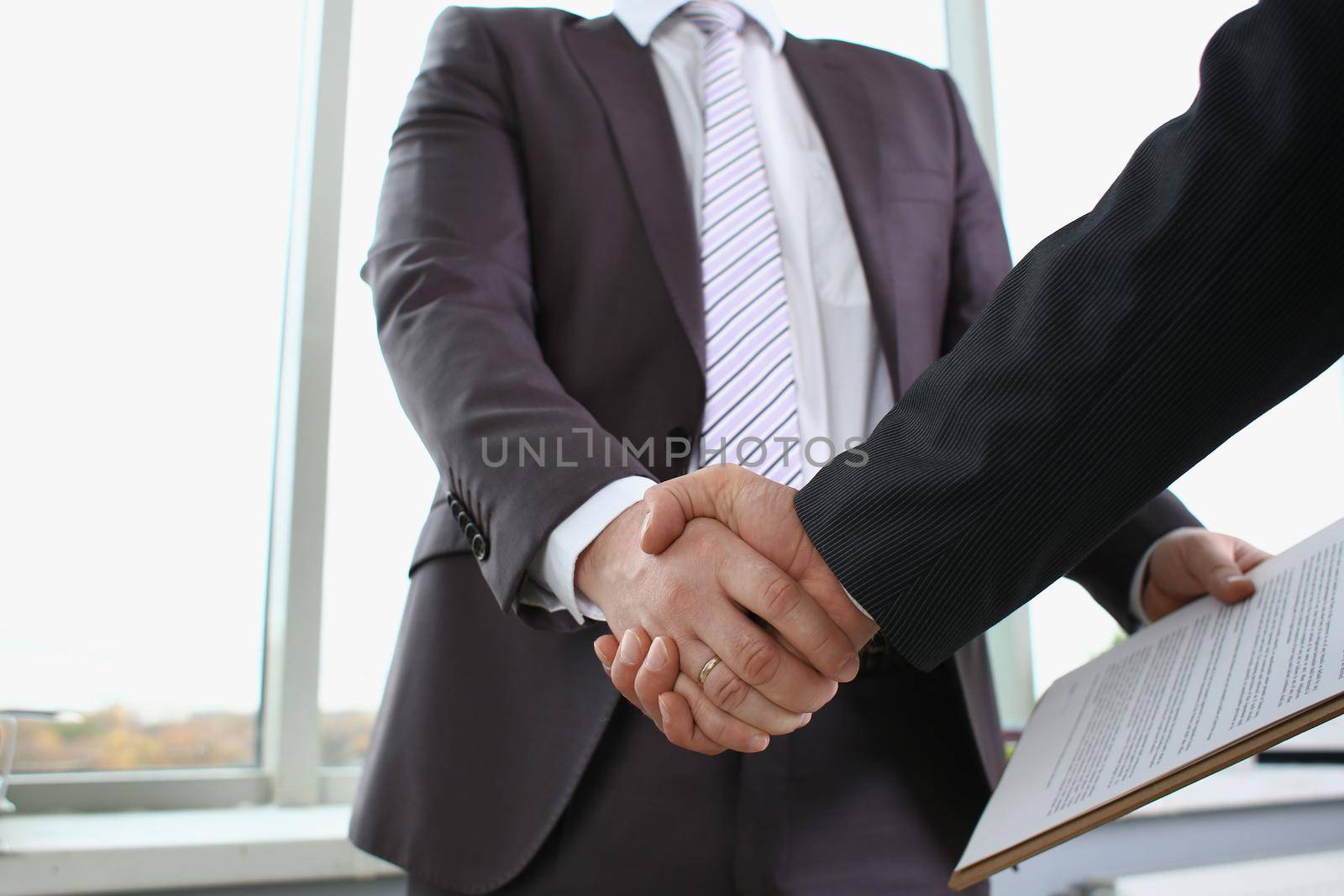 Man in suit shake hand as hello in office by kuprevich