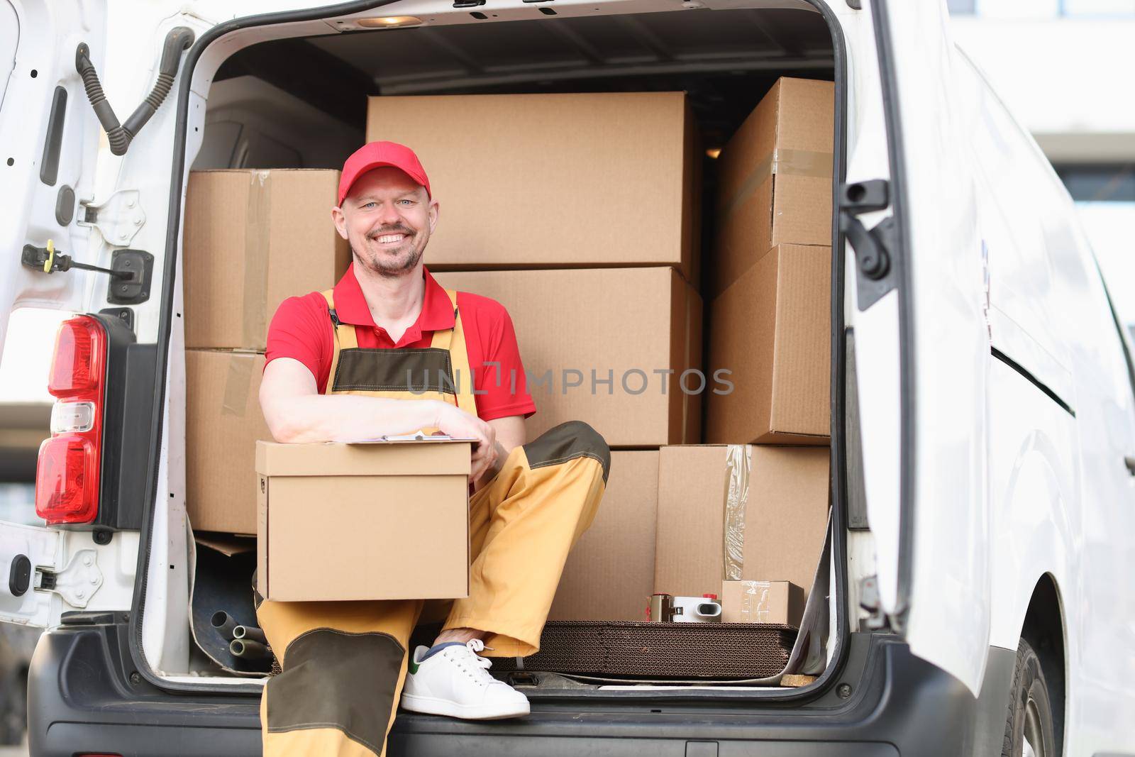Man courier holding a parcel while sitting in the truck by kuprevich