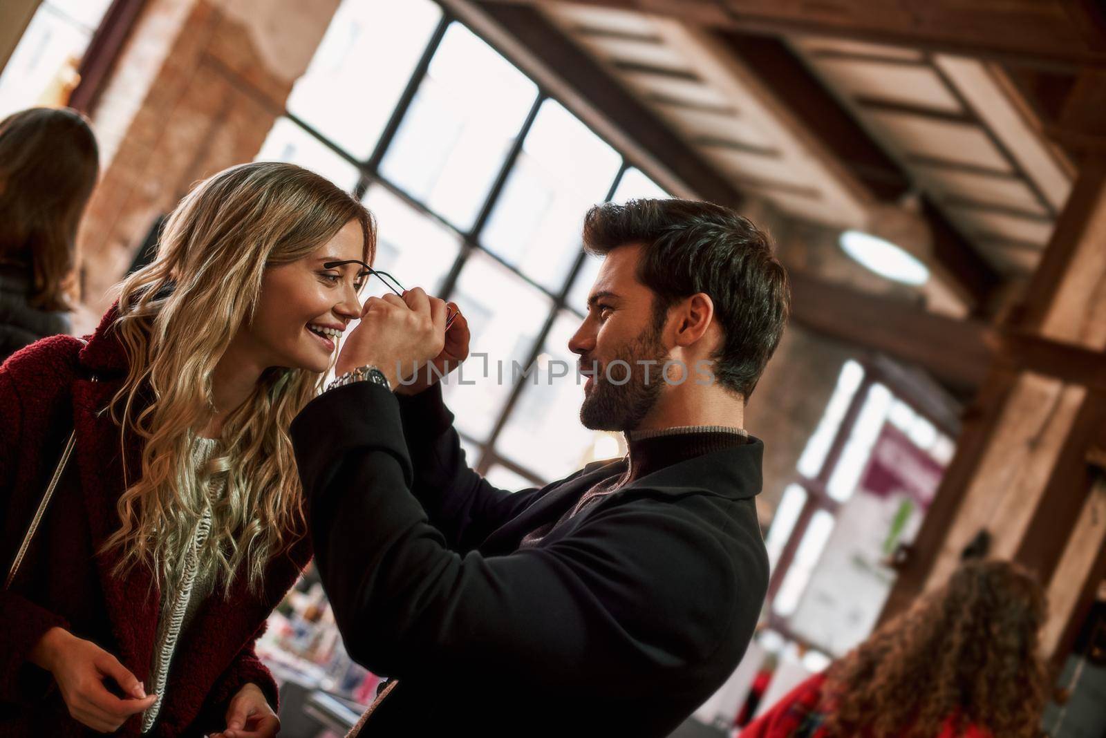 Happy young couple are buying sunglasses at small street market by friendsstock