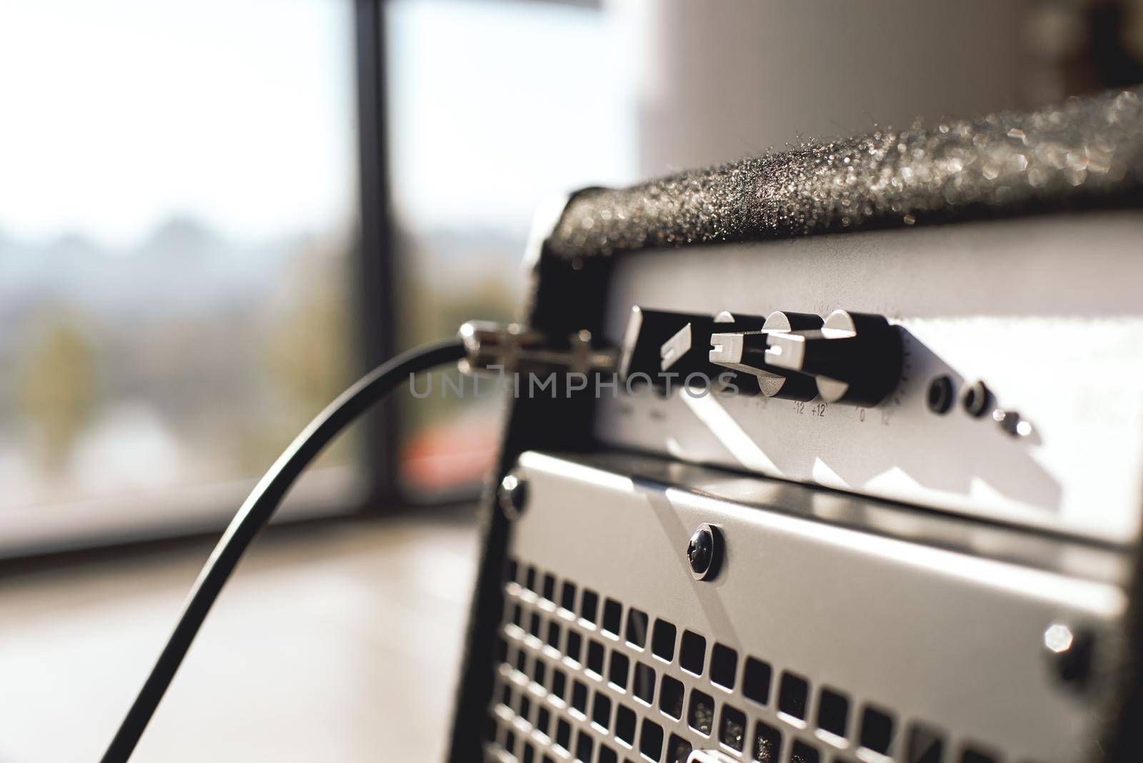 Powerful sound of your guitar. Close-up view of guitar amplifier with cable audio jack. by friendsstock
