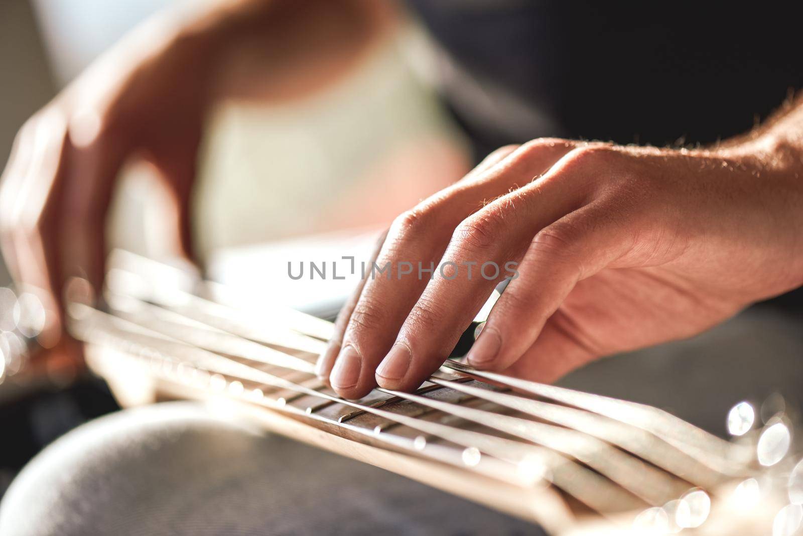 Feeling my instrument...Close-up of male hands touching metal strings of guitar by friendsstock