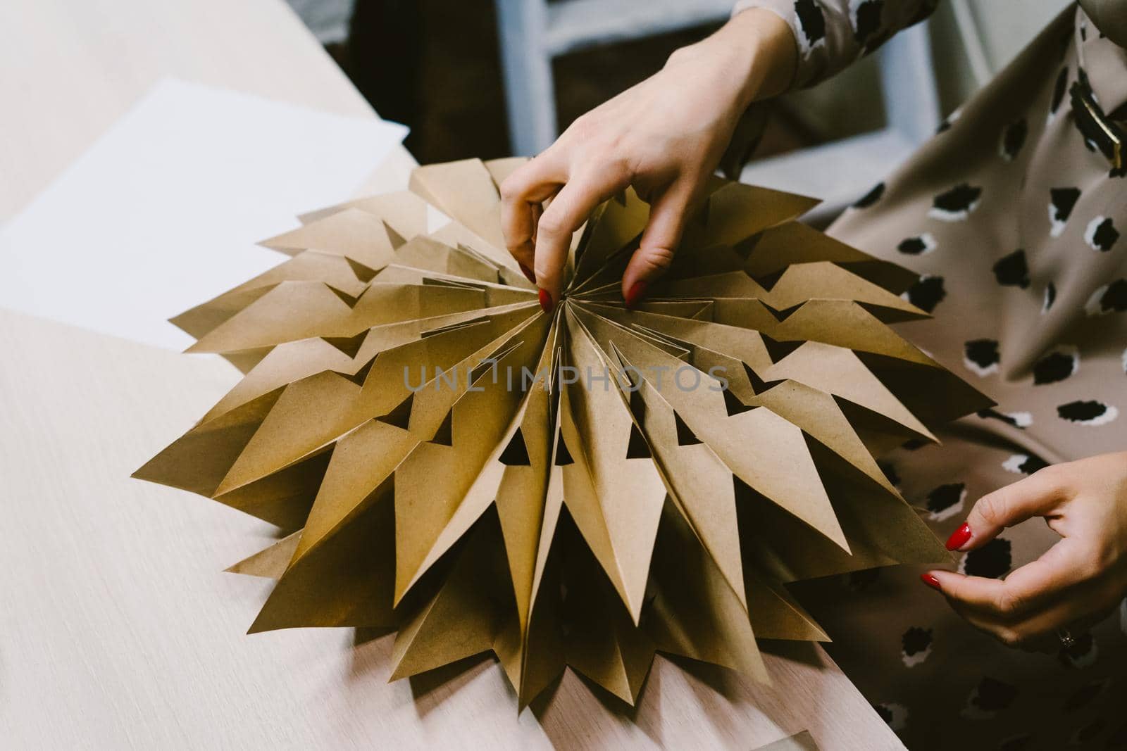 The origami stage. DIY personalized xmas decoration. Creating hand made christmas ornaments. Step by step instructions. Snowflake or three-dimensional star made of kraft paper.