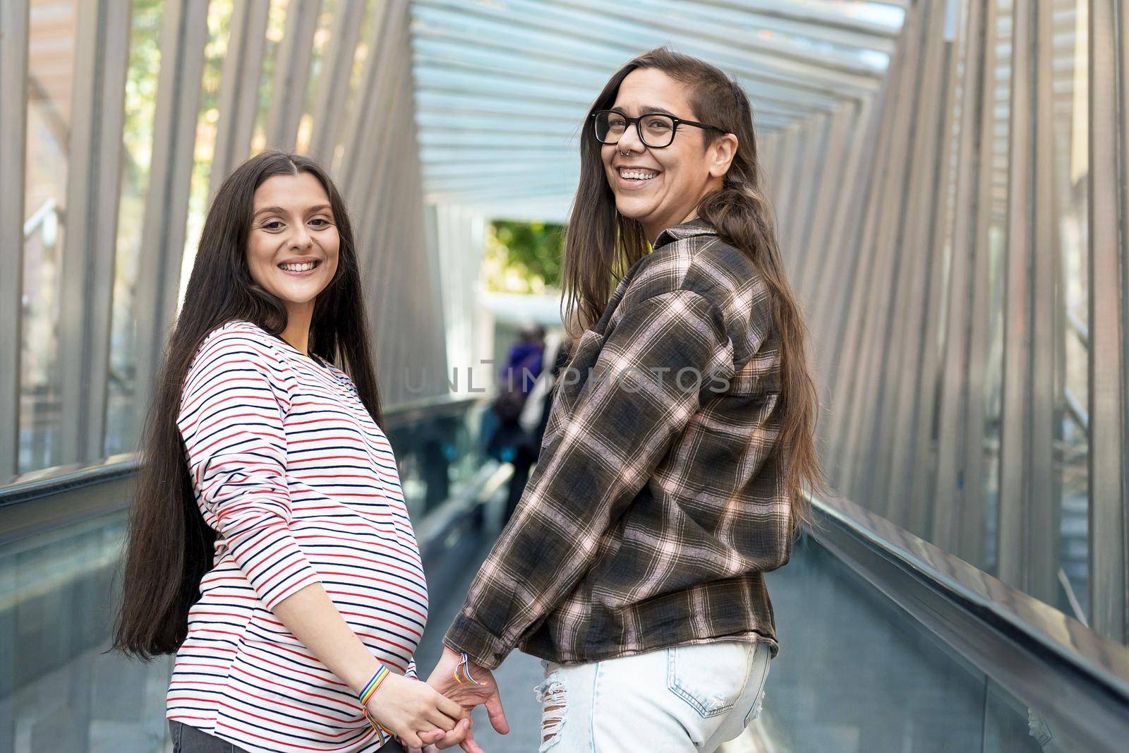 Close up of Lesbian Pregnant Couple holding hands outdoors. by HERRAEZ