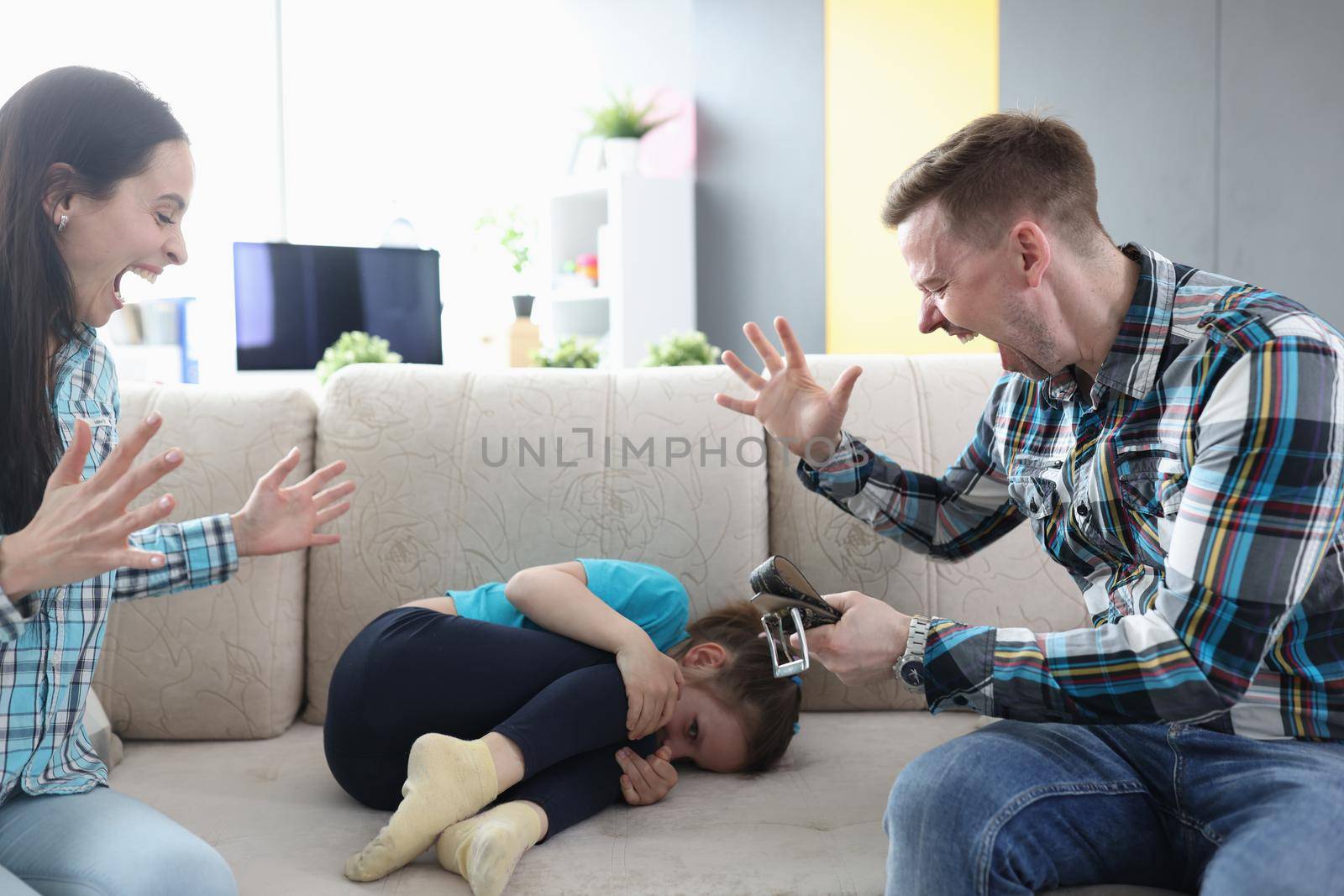 Dad and mom are shouting at their daughter at home, close-up. The child is afraid of punishment. Emotional domestic violence, aggressive parents